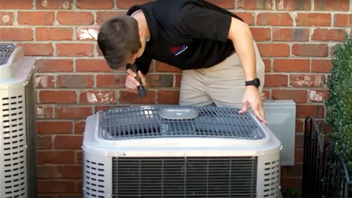 Jake, one of our home inspectors, looking at an air condition unit outside of a house